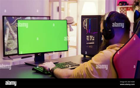 Over shoulder footage of man playing video games on computer with green ...
