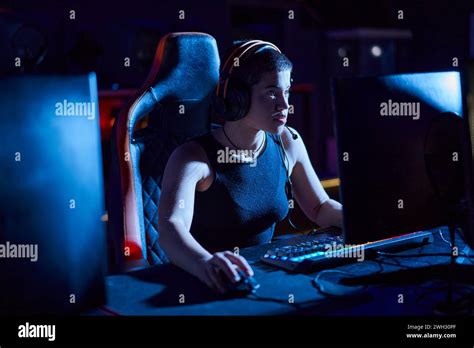 focused gamer in headphones looking at computer monitor while thinking ...