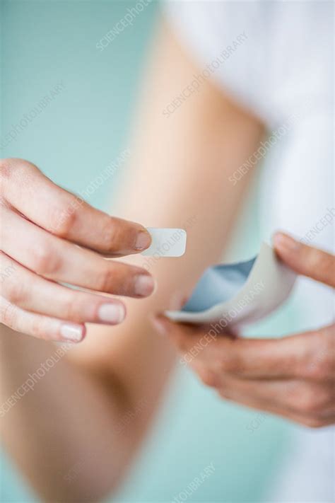 Woman applying a patch - Stock Image - C035/6985 - Science Photo Library