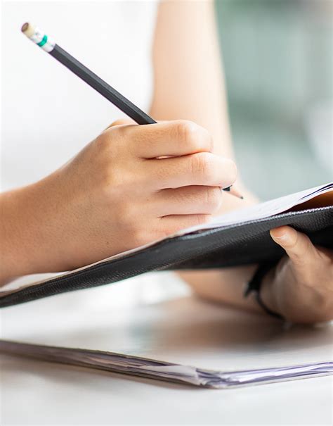 An Asian female is taking notes on her notebook for online classes ...