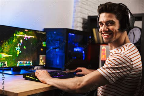 Foto de Image of cheerful gamer man playing video games on computer ...