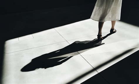 Download A Woman In A White Dress Standing In The Shadow Of A Light ...